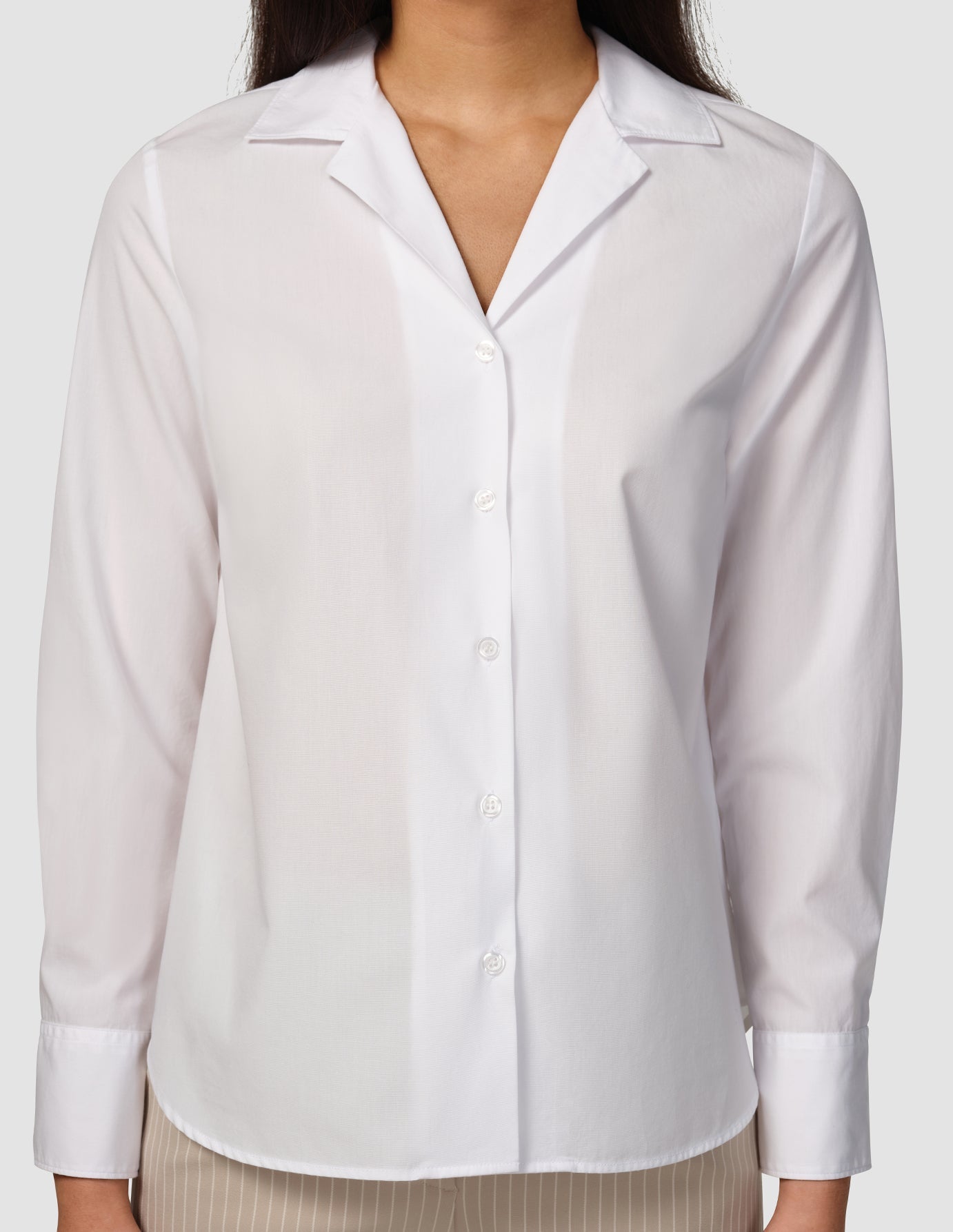A woman wearing a white, long-sleeved Madison Shirt White in a button-down style with a notched collar.